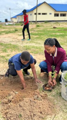 Lidya John and a students planting a tree